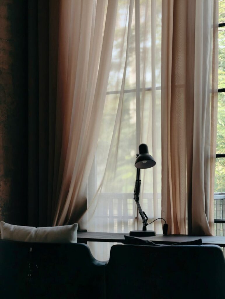 Sunlight streams through curtains onto a cozy workspace with a lamp in Haiphong, Vietnam.
