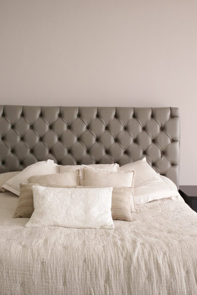 a bed with a white comforter and pillows