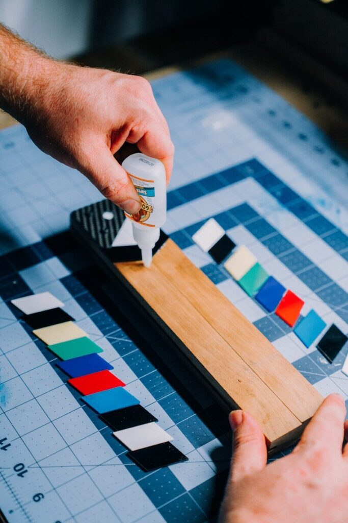 a person using a glue stick on a piece of wood