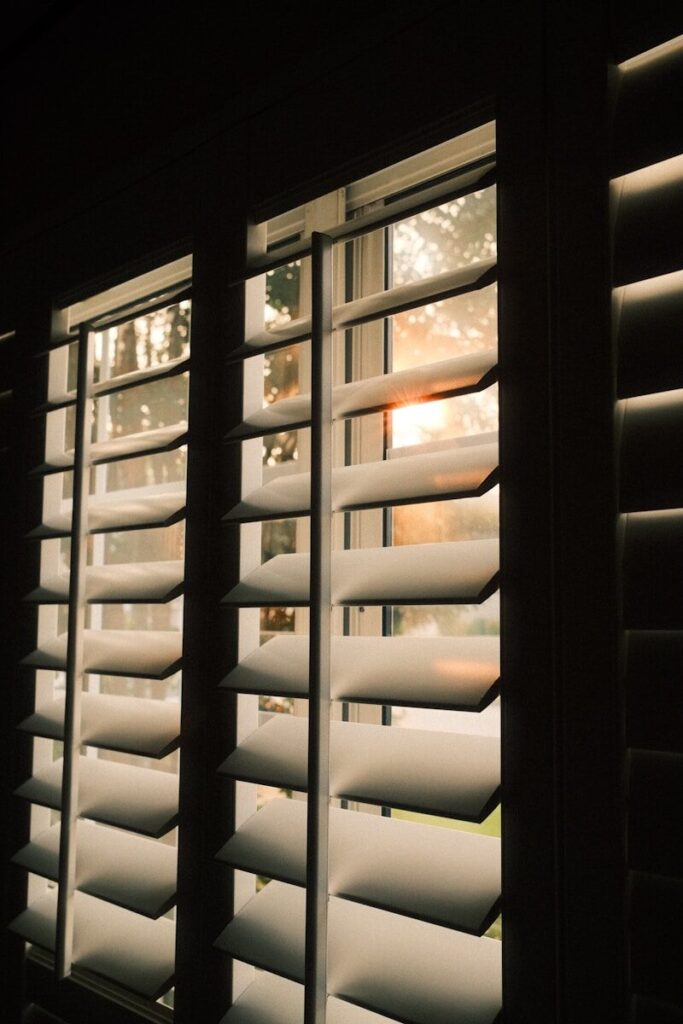 Sunlight streams through open window shutters.