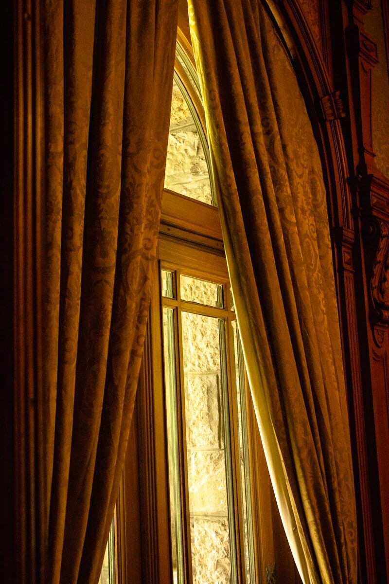 a window with curtains and a clock on the wall