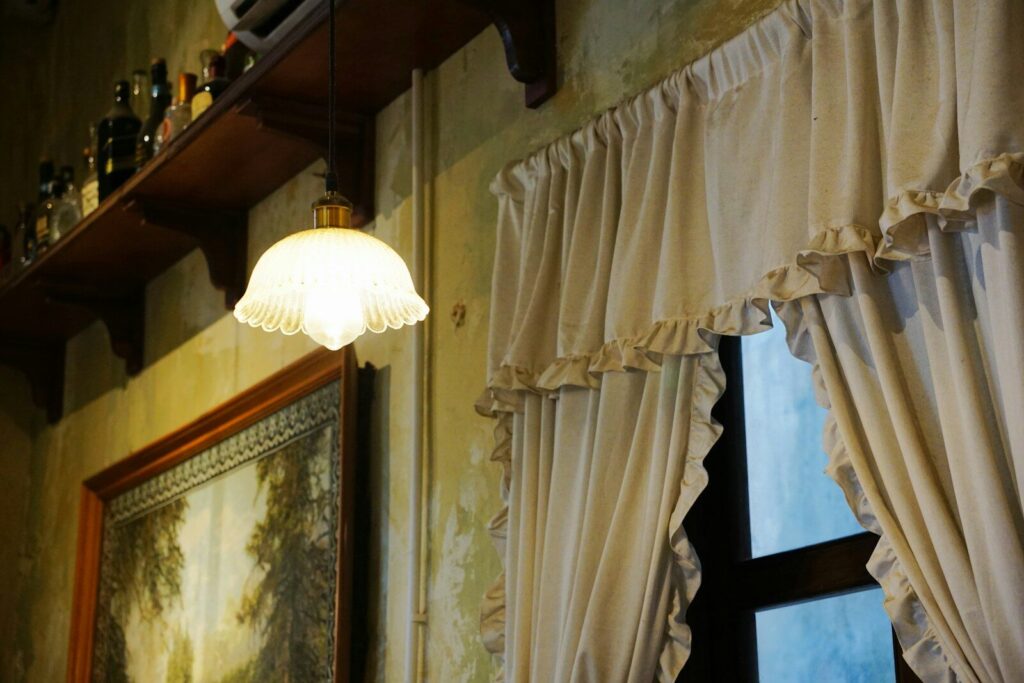 Vintage lamp hangs near a window with curtains.
